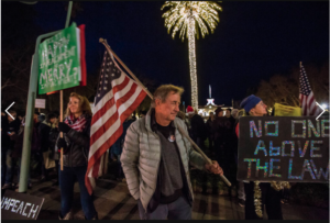 Activist, Mike Smith, shoulders large American Flag at nighttime rally